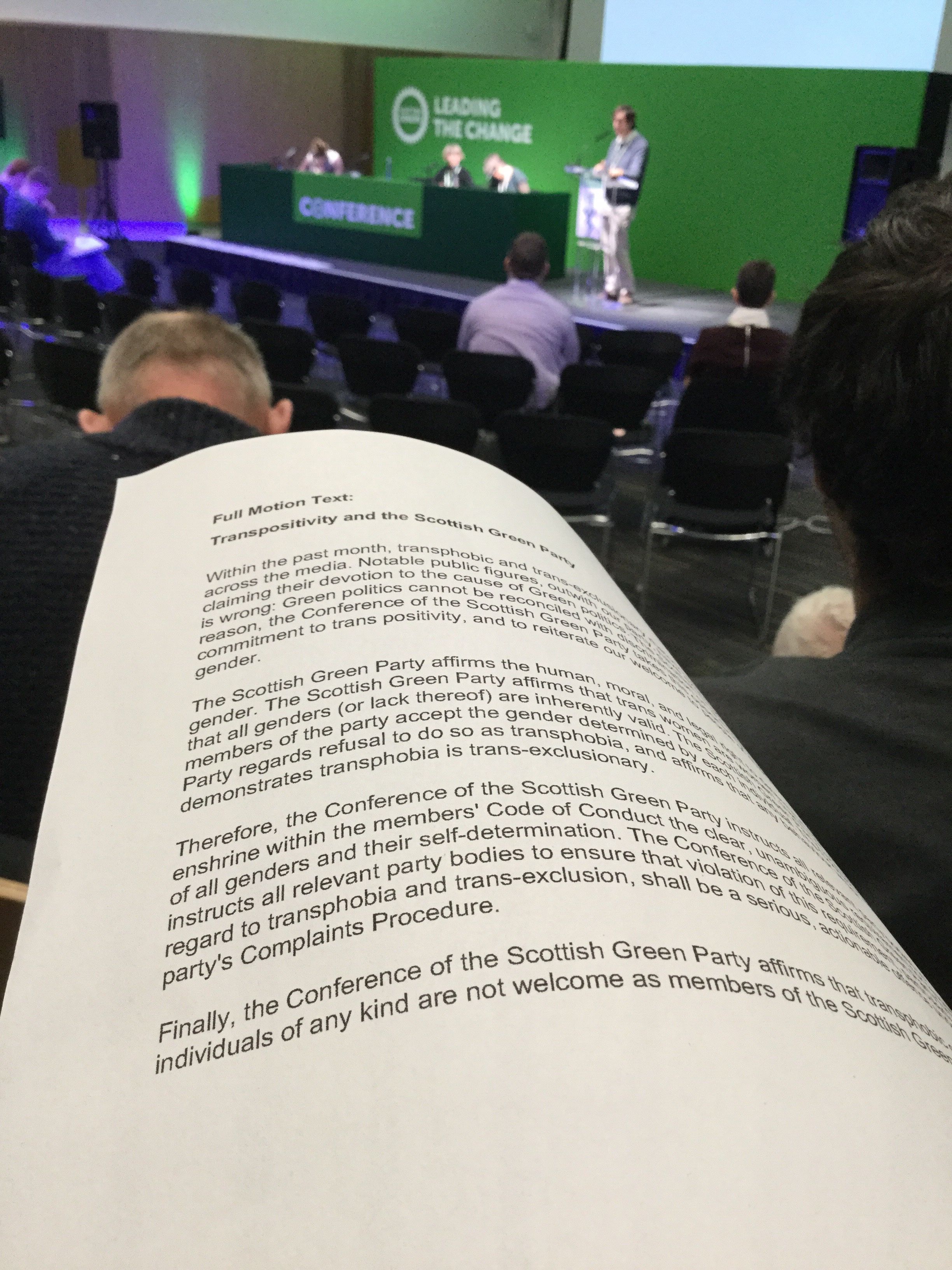 Text of the Scottish Green Party’s trans-positivity motion, with the conference platform in the background