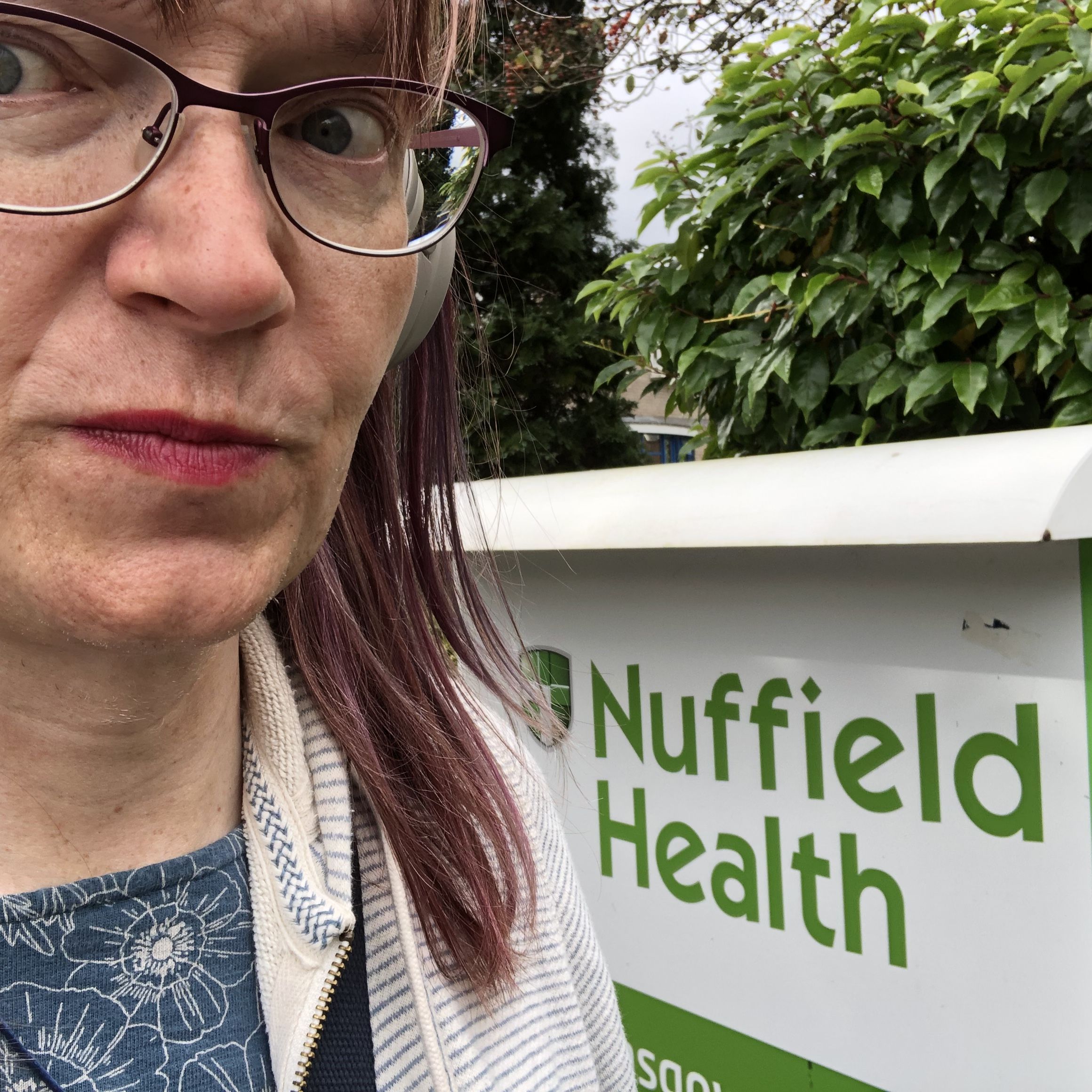 Anna standing pensively next to a sign reading ‘Nuffield Health Glasgow Hospital’