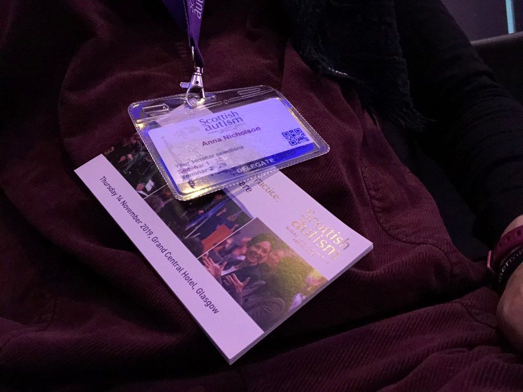 Anna’s lanyard with her conference badge and a conference booklet attached