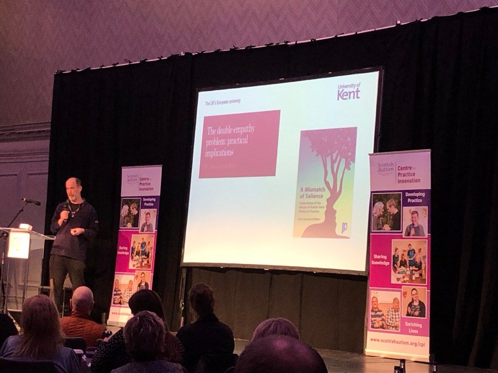 Damian Milton at a lectern, with his opening slide on practical implications of the double empathy problem