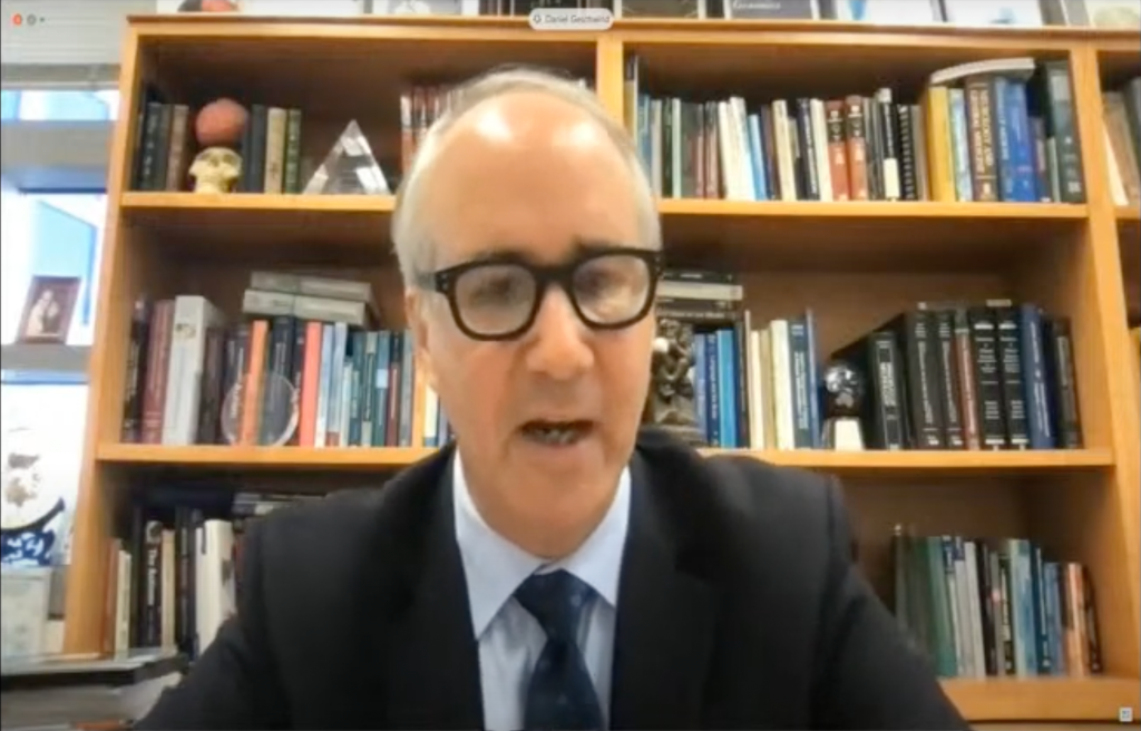 Daniel Geschwind, a middle-aged white man wearing a dark suit and tie and black-rimmed glasses. He is seated in front of a bookshelf.